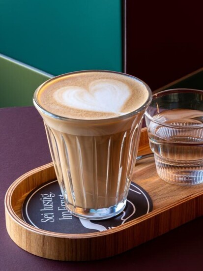 Schaumiger Cappuccino, im schönen Ernst auf einem Tablett serviert.